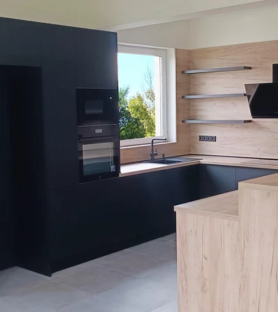 Tato kuchyň kombinuje černé matné skříňky s dřevěným dekorem, který dodává kuchyni teplý a přírodní vzhled. Kuchyň je vybavena kvalitními spotřebiči značky Electrolux. 