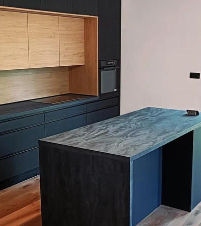 Moderní kuchyňská sestava do stropu s ostrůvkem. Nabízí dostatek pracovní plochy i úložného prostoru. Ostrůvek se dá využít také k posezení. Jedná se o kombinaci černého hlubokého matu a dekoru dřeva. Sestava je postavená na dřevěné masivní podlaze.